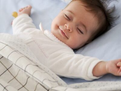 image of a baby sleeping happily in bed